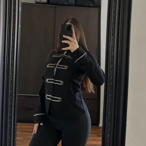 Randig kavaj från KappAhl - Snygg svart kavaj från KappAhl med guldiga knappar och dekorativa detaljer. Den har en stilren design med långa ärmar och en rak passform. Perfekt för att ge en elegant touch till din outfit.🥰🥰🥰