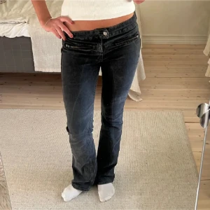 Svarta bootcut jeans - Snygga svarta bootcut jeans med låg midja och dragkedjedetaljer framtill. Perfekta för en stilren look. Passar bra till både sneakers och klackar.