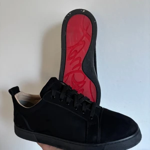 Louboutin skor - Snygga svarta sneakers med en ikonisk röd sula. Skorna har snörning och en stilren design som passar perfekt för en trendig look. Perfekta för dig som vill ha något unikt i garderoben.