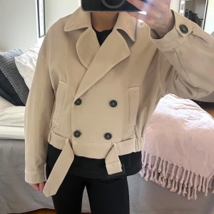Beige trenchcoat med bälte - Snygg beige trenchcoat med knappar och bälte i midjan. Nästan aldrig använd, så i nyskick!💓