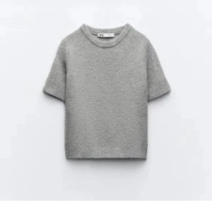 Grå stickad tröja från Zara - Säljer en stilren grå stickad tröja från Zara. Tröjan är kortärmad och har en croppad passform som ger en modern look. Perfekt för lager-på-lager eller att bära som den är. 🩶