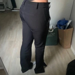 Svarta kostymbyxor - Snygga svarta kostymbyxor med låg midja och bootcut.Byxorna har slit ned till och inga deffekter!!💕