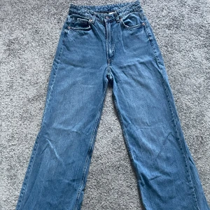 Blå jeans med vida ben - Snygga blå jeans med hög midja och vida ben. Klassisk femficksdesign med knapp och dragkedja framtill. Perfekta för en avslappnad stil. Innebenslängd 76cm.