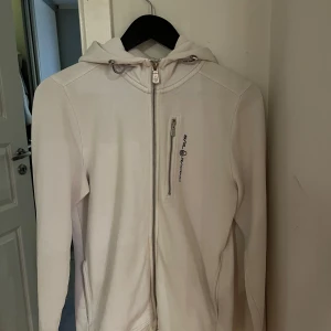 Vit huvtröja från Sail Racing - Säljer min zip hoodie ifrån Sail Racing då jag inte använder den längre. Tröjan har en justerbar luva den är väldigt bekväm. Fint skick och använt några få gånger. Pris kan diskuteras. 