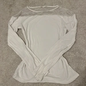 Vit långärmad topp med spetsdetalj - Supersöt vit långärmad topp med transparent spets upptill vid axlar och halsringning. Inga defekter 💞