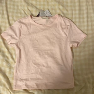 Ljusrosa t-shirt från Gina Tricot - Supersöt ljusrosa t-shirt från Gina Tricot, modell Basically Basics. Enkel design med rund hals och korta ärmar. Mjuk och skön bomull som känns chill mot huden. Perfekt att matcha med jeans eller kjol för en clean look. Helt oanvänd, nytt pris 159kr. Säljs för 50kr 