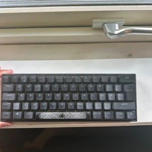 Corsair tangentbord - Bilderna visar ett kompakt mekaniskt tangentbord från Corsair med RGB-belysning. Tangentbordet har en nordisk layout och är perfekt för gaming eller studier. Snygg design med bakgrundsbelysning som lyser upp tangenterna i rött. Passar dig som vill ha en stilren och portabel lösning till datorn.