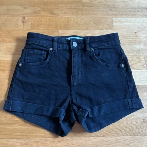 Svarta jeansshorts från Bershka - Svarta jeansshorts från Bershka. Shortsen har uppvikta benslut, bälteshällor och knappstängning fram. Endast använda en gång. 