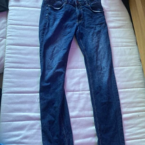 Mörkblå raka jeansbyxor - Snygga mörkblå jeansbyxor med klassisk femficksdesign och raka ben. Jeansen har normal passform och är tillverkade i slitstarkt denimtyg. Perfekta för dig som gillar en enkel och tidlös look.