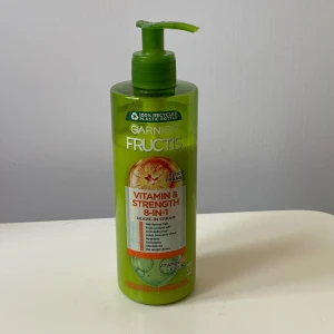 Garnier Fructis Vitamin & Strength 8-in-1 - Grön pumpflaska med Garnier Fructis Vitamin & Strength 8-in-1 leave-in cream, doft av blodapelsin. Innehåller vitamin C och biotin, 400 ml. Flaskan är tillverkad av återvunnen plast och har en fräsch, citrusinspirerad design. Tagit lite ur den. Säljer då den inte passar mitt hår 