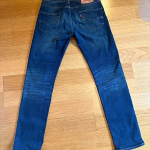 Levi's 511 blå jeans W29 L32 skön wash - Säljer ett par Levi's 511 jeans i blå tvätt med snyggt slitna detaljer och skön wash. Modellen är slim fit med raka ben och normal midja.