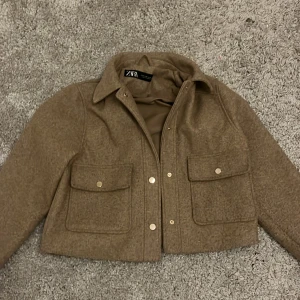 Zara kappa beige - Kappa från zara i xs färgen beige Andvänd och pytte lite nopprig synns inte så tydligt guld knappar ny pris ca 550,  säljer pga inte min stil 