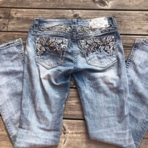Miss Me BOOTCUT - Säljer ett par ljusblå bootcut jeans från Miss Me med snygga broderade detaljer och paljetter på bakfickorna och framfickorna. Jeansen har slitningar och en liten reva på ena benet. Perfekt för dig som gillar statement-jeans med y2k! Köpa på vinted och är endast testade! Storlek w26. Fråga gärna om mått och andra allmänna frågor !🩷de är bootcut och inga hål förutom design revan vid knäet!