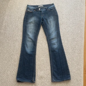 Blå bootcut jeans från Diesel - Jätte snygga wintage jeans Diesel med bootcut passform och låg midja. Jeansen har klassisk femficksdesign, slitningar och tvättade detaljer för en cool look. Materialet är jeans och de har dubbla knappar i midjan. Perfekta för dig som den coola 2000s tals locken💗💗