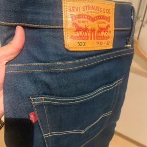 Levi's 520 mörkblå jeans W32 L32 - Säljer ett par Levi's 520 jeans i mörkblå denim med klassiska kontrastsömmar och den ikoniska läderpatchen bak. Modellen har en avslappnad passform och är tillverkad i slitstarkt bomullsjeans. Perfekta för dig som gillar en tidlös look.