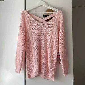 Ljusrosa stickad tröja med korsad rygg - Superfin ljusrosa stickad tröja från coal & honey med snygga flätade detaljer längs sidorna och korsade band i ryggen. Tröjan har lång ärm och en loose passform. Perfekt för alla storlekar beroende på hur man vill att den ska passa. Materialet är mjukt och luftigt. Några trådar som sticker ut lite här o där men syns inte så mycket.