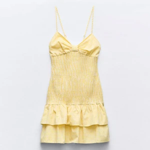 Gul rutig kortklänning med volanger - Supersöt gul klänning från Zara med gingham mönster och smockad midja. Använd 1 gång. 