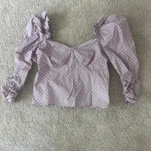 Lila prickig top från By Malina - Lila prickig top från By Malina som är helt oanvänd! Tröjan har fina detaljer som Puff ärmar och volanger, i storlek M. Pris kan diskuteras! Hör av dig om du skulle ha någon fråga💕