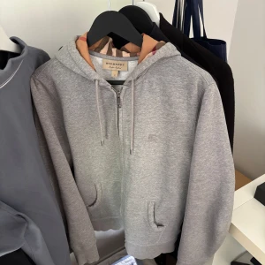 Burberry hoodie grå - Säljer nu en grå Burberry hoodie, og modellen!med klassiskt rutigt foder i huvan. Pris går att diskutera!                                                                Skick: 8/10  ”har en liten fläck på axeln se bild”          Storlek: M   ”passar S”                                                              Skriv om ni har funderingar!