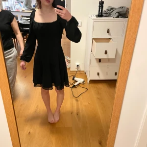 Svart klänning med volangärm från Pamela x Naked - Supersöt svart klänning från Pamela x Naked med en rosett i ryggen. Klänningen är i storlek 32 och är nästan oanvänd. 🩷