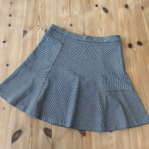 Jättefin rutig kortkjol från Stradivarius - Säljer en svartvit rutig kjol från Stradivarius i storlek 38/M. Kjolen har en utsvängd form och är i ett hundtandsmönster. Perfekt till skolan eller till en enkel topp/stickad tröja. Pris kan diskuteras vid snabb affär! 