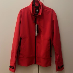 Röd jacka från Texstar med dragkedj och passar dom som har L  - Säljer en röd jacka från Texstar i storlek XL.man passa dom som har L bra  Jackan har hel dragkedja framtill, två fickor med dragkedja och justerbara ärmslut. Perfekt för dig som vill ha en stilren och sportig look.
