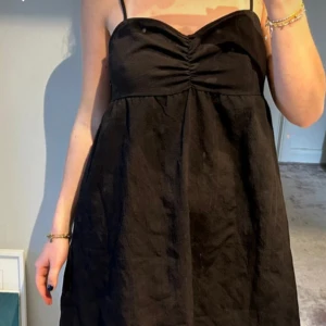 Svart klänning med smala axelband - Säljer en svart klänning med smala axelband och rynkad detalj vid bysten. 