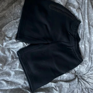 Svarta shorts från Nike - Svarta shorts från Nike med diskret logga på benet och dragkedjeficka. Klassisk passform och tillverkade i mjukt material som passar perfekt för träning eller avslappnade dagar.