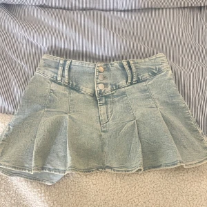 Ljusblå jeanskjol - Säljer en ljusblå jeanskjol. Kjolen har utställd form och markerade sömmar som ger en cool look. stretchigt material. Midjemått: 72 cm