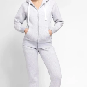 Ljusgrå hoodie med dragkedja - Säljer en ljusgrå hoodie med dragkedja och huva. Tröjan har långa ärmar, fickor framtill och vita snören i huvan. Perfekt för en avslappnad stil.