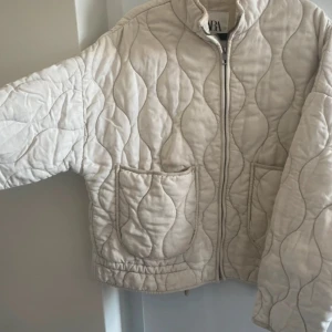 jacka från Zara - Säljer en beige quiltad jacka från Zara med dragkedja framtill och två stora fickor. Jackan har en oversized passform och lång ärm!