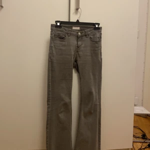 Grå bootcut jeans från Lindex, stretchiga  - Säljer ett par gråa bootcut jeans med normal passform och klassisk femficksdesign. Jeansen har knapp och dragkedja framtill och är tillverkade i ett mjukt denimtyg. Perfekta för dig som gillar en tidlös och enkel stil.