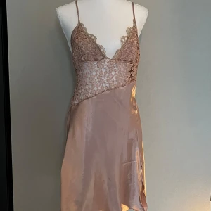 Champagnefärgad slipklänning med spets - Säljer en champagnefärgad slipklänning med tunna axelband och vacker spets upptill. Mindre i storleken 