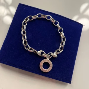 Silverfärgat armband från Thomas Sabo - Säljer ett chunky silverfärgat armband från Thomas Sabo med en rund berlock. Länkarna är ovala och armbandet har ett klassiskt karbinlås. Perfekt för dig som gillar statement-smycken.