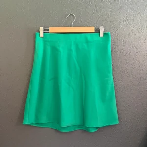 Grön kjol från BikBok - Säljer en snygg grön kjol från BikBok i en enkel och stilren design. Kjolen har en rak passform och är tillverkad i ett slätt material som ger en fräsch look. Perfekt att matcha med en crop top eller t-shirt.