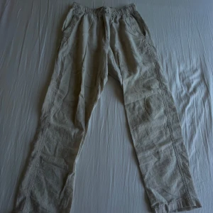 Beiga linnebyxor från H&M - Säljer ett par beiga linnebyxor från H&M med resår i midjan och sidofickor. Byxorna har en avslappnad passform och är perfekta för varma dagar. Lätta och luftiga i materialet.