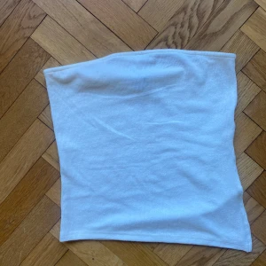 Vit tubtopp  - Säljer en enkel och stilren vit tubtopp från Pimkie. Toppen är ribbad och ärmlös, perfekt att matcha med jeans eller kjol för en clean look.