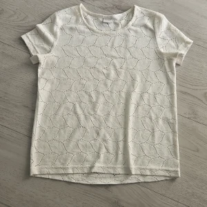 Vit mönstrad t-shirt från Jacqueline de Yong - Säljer en vit t-shirt från Jacqueline de Yong med korta ärmar. Den är i bomull med håligt blad mönster 💞Säljer för den inte används, inget fel på den (storlek xs)