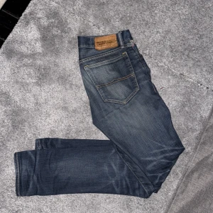 Blå jeansbyxor från Denim & Supply Ralph Lauren - Säljer ett par klassiska blå jeans från Denim & Supply Ralph Lauren. Jeansen har fem fickor, raka ben och snygga slitningar. Tillverkade i 100% bomull med en skinnpatch bak i midjan.
