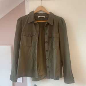 Olivgrön tunn jacka med knappar - Säljer en olivgrön tunn jacka från co couture. Jackan har långa ärmar och knäppning. Passar perfekt på våren/sommaren. Säljer eftersom den är lite för kort i armarna på mig.