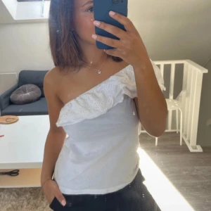 Vit one shoulder topp med volang - Säljer en vit one shoulder topp med volangdetalj. Storlek Xs