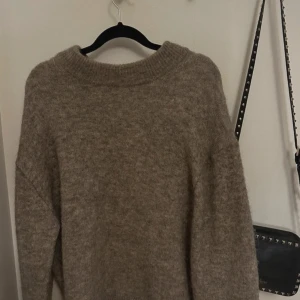 Beige alpacaull stickad tröja H&M - Säljer en mysig beige tröja från H&M i en mjuk ull- och alpackablandning. Tröjan har en klassisk rund hals och långa ärmar, perfekt för kyligare dagar. En stilren och bekväm baströja för garderoben.