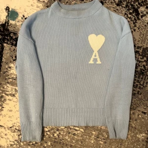 Ami Paris Tröja - Säljer en snygg ljusblå stickad tröja från Ami med en fin unique design. Tröjan är perfekt för kyligare dagar och passar med olika stiler skriv till mig för mer info