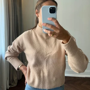 Beige tröja från & Other Stories - Säljer en stilren beige tröja från & Other Stories. Tröjan har en hög krage och långa ärmar, perfekt för kyligare dagar. Den är tillverkad i ett mjukt material som ger en skön känsla mot huden. Passar utmärkt till både jeans och kjol.