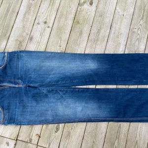 Blå Nudie Jeans - Snygga blå jeans från Nudie Jeans, modell Slim Jim i färgen Greentone. Tillverkade i 100% bomull med en slim passform. Klassisk design med fem fickor och orange sömmar. Perfekta för en stilren look.