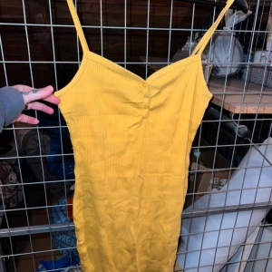 Gul ribbad klänning med smala axelband - Snygg gul ribbad klänning med smala axelband och knappar framtill. Storlek L men passar M oxå