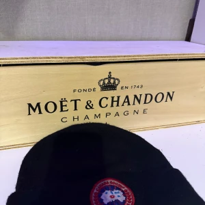 Svart mössa med broderad detalj - Snygg svart mössa från Canada goose en broderad detalj framtill. Perfekt för att hålla värmen under kyliga dagar. Enkel och stilren design som passar till det mesta.