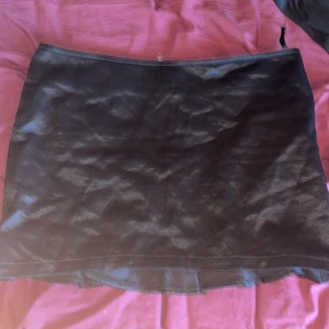 Svart kjol från Rock by Sweden - Snygg svart kjol från Rock by Sweden med dragkedja bak och coola nitar som detaljer. Kjolen har en volangkant längst ner som ger en extra touch. Tillverkad i en blandning av bomull och viskos för en skön känsla.