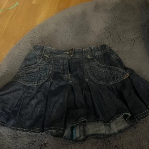 Mörkblå jeanskjol med fickor - Snygg mörkblå jeanskjol med dekorativa sömmar och praktiska fickor fram och bak. Kjolen är i stolek 134 barn men passar nästan mig som är 169cm bara att den är lite liten i Midjan