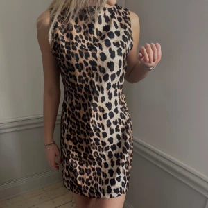 Leopardmönstrad klänning - Snygg och trendig leopardmönstrad klänning i en kort modell. Klänningen är ärmlös och har en figurnära passform som framhäver silhuetten. Perfekt för en utekväll eller en speciell tillställning.